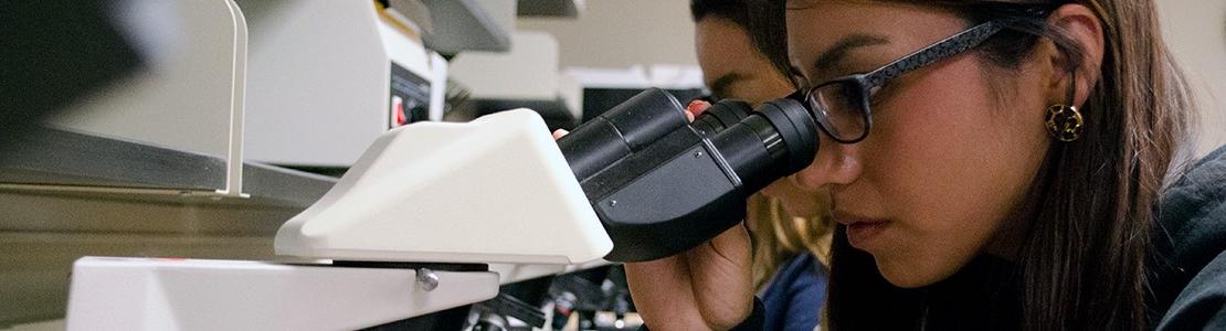 student looking into microscope